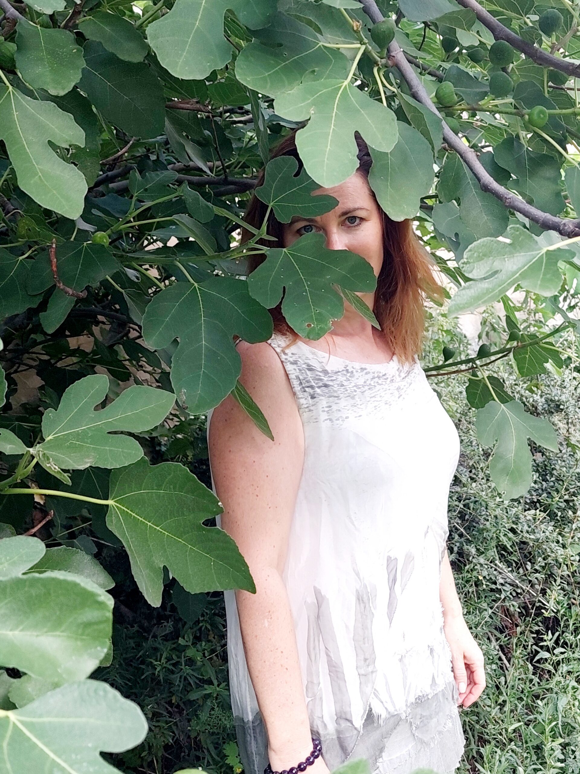 Portrait of Veronika Zuffova-Kuncova standing among green leaves in a white dress